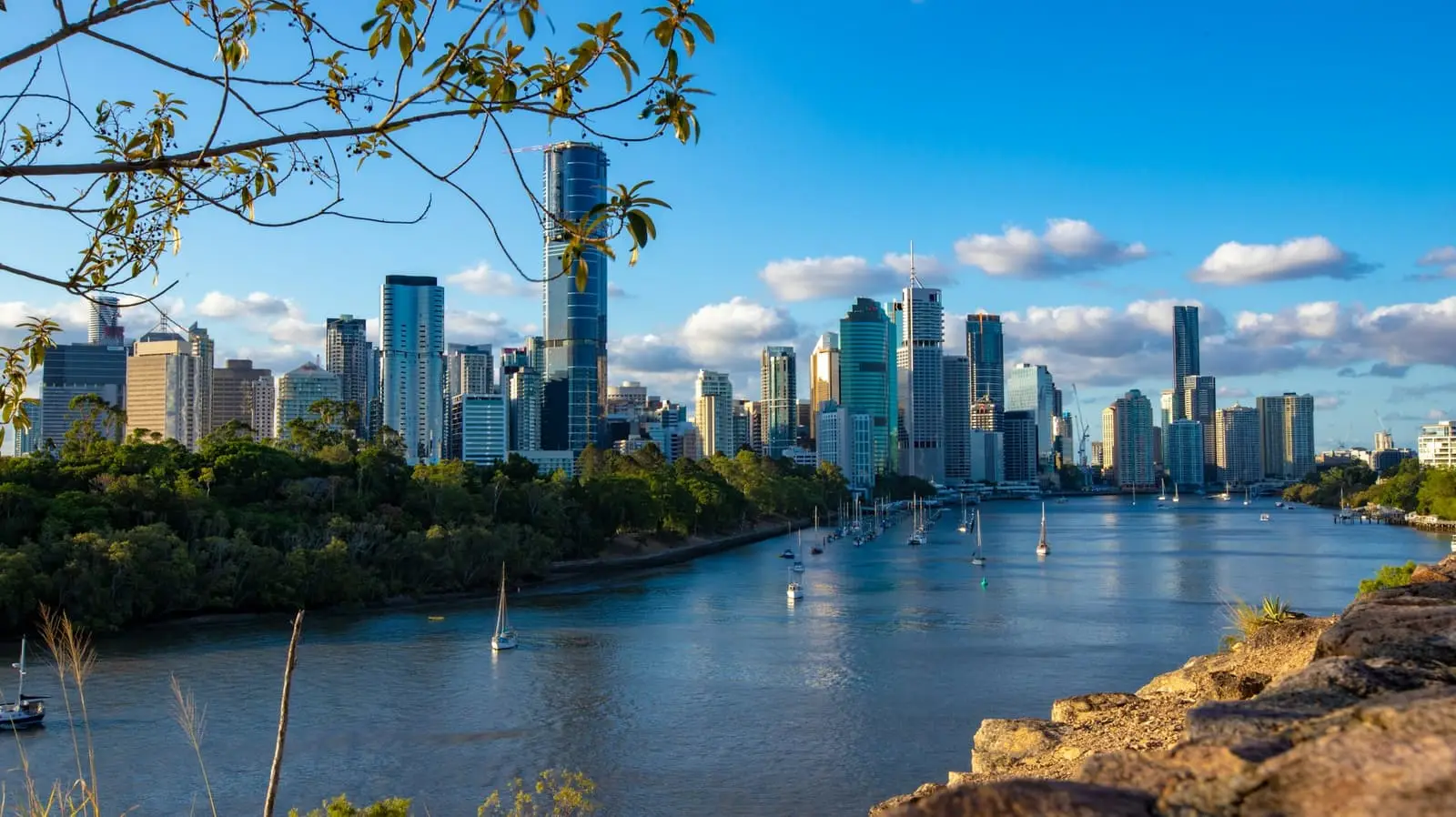 High-rise city buildings beside the Brisbane River from Kangaroo Point Cliffs in daylight