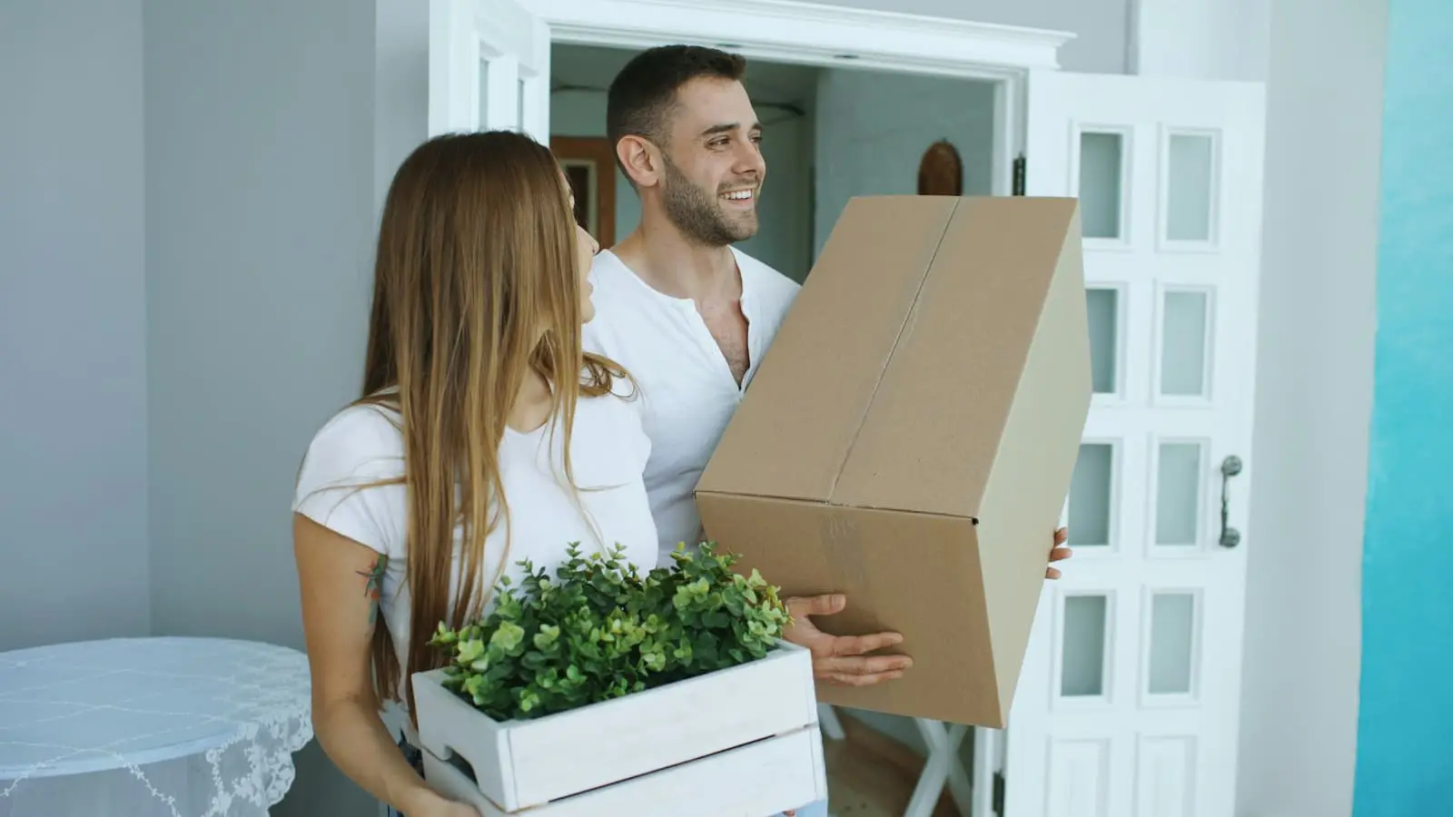 Couple carrying moving boxes into their new home