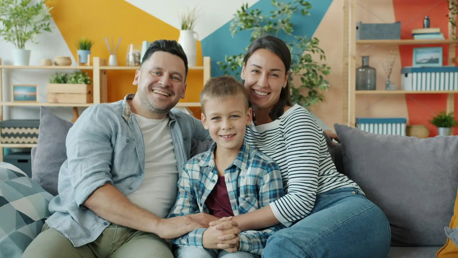Happy family of three sitting together on a couch