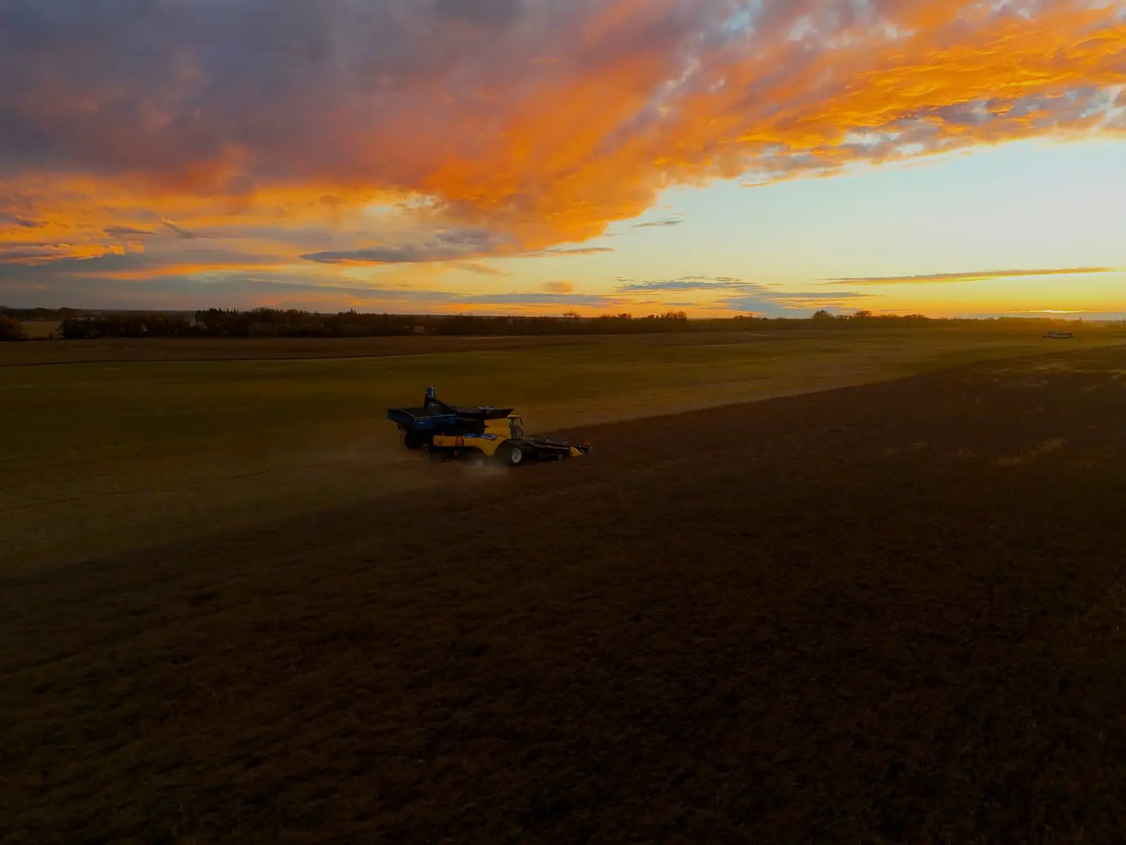 Tractor in a field with the sun setting behind it