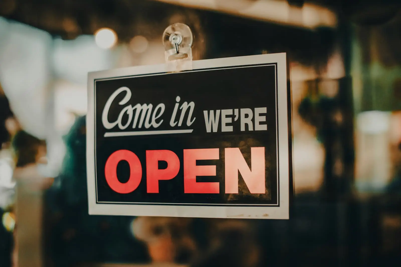 Sign hanging in a shop door welcoming customers that the store is open