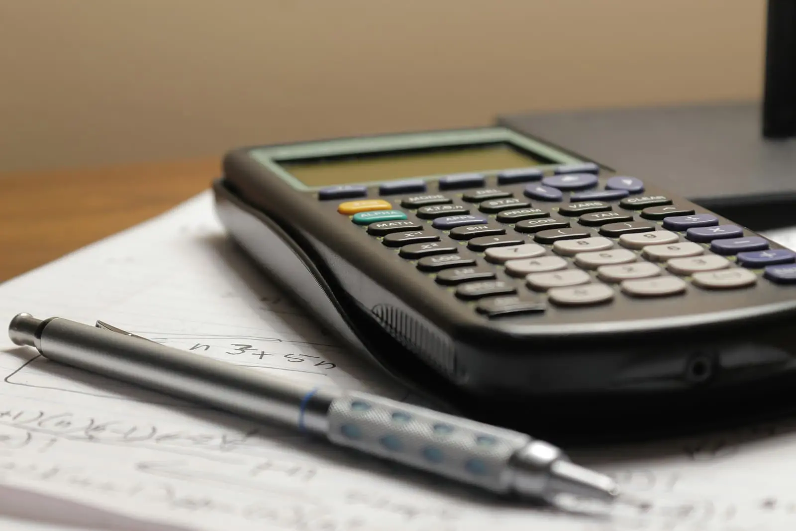 Calculator and pen resting on a sheet of paper