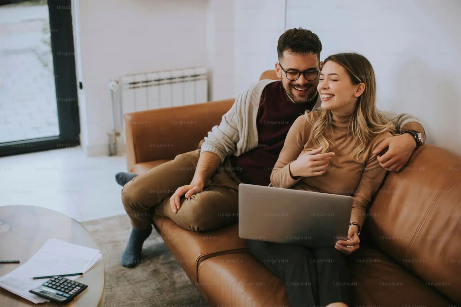 Young couple sitting together on a sofa at home using a laptop