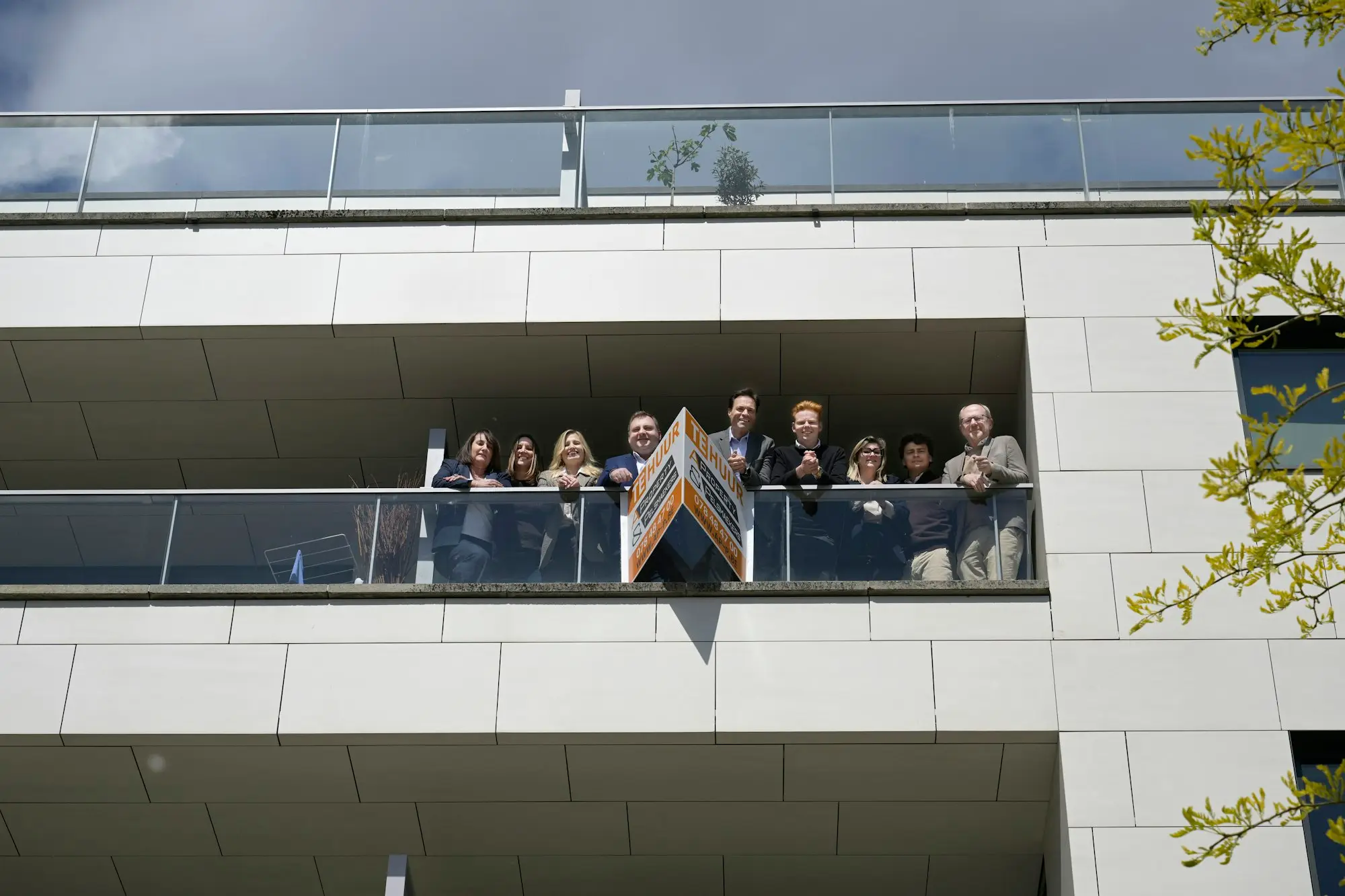 Modern apartment building with people on an upper-level balcony, the kind of investment property a lender wants rental evidence for