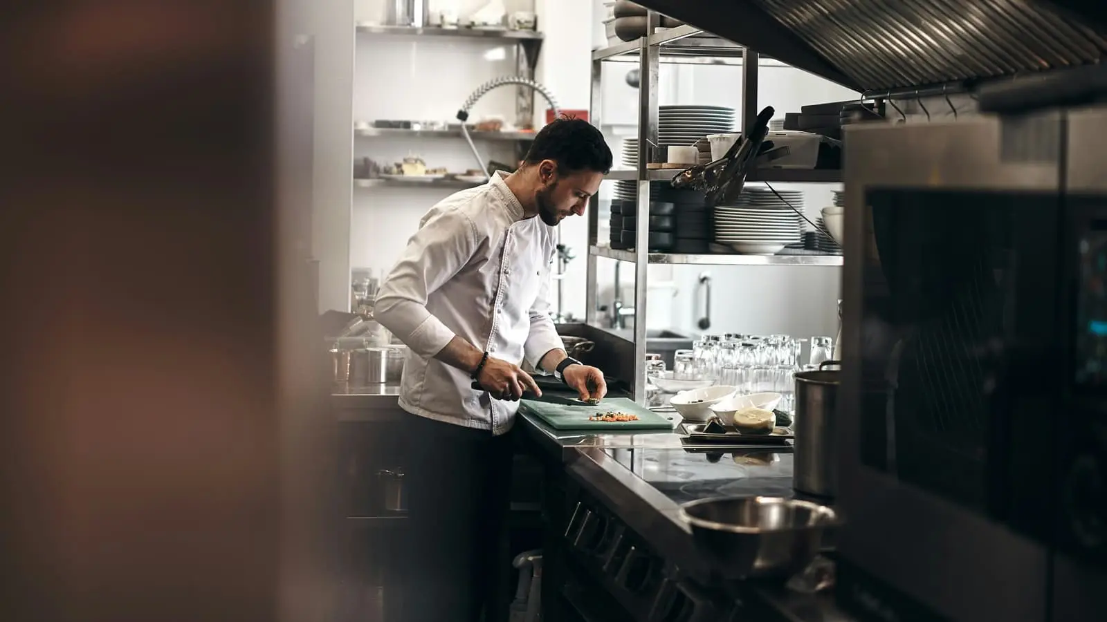 Chef chopping vegetables on a bench in a restaurant kitchen