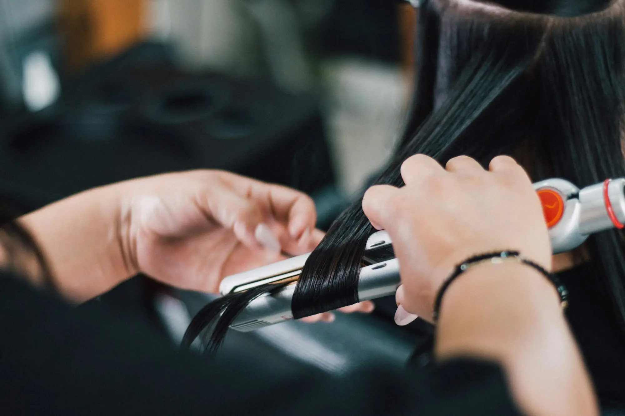 Self-employed hairdresser straightening a client's hair, a sole trader with about a year of trading history