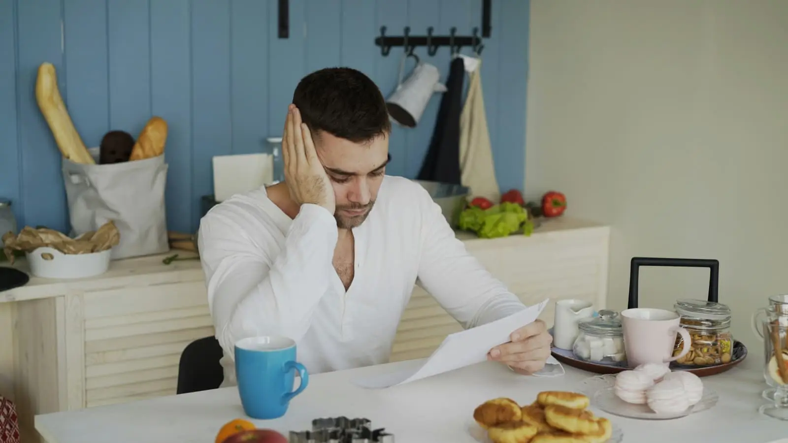 Person at a kitchen table reading documents, thinking through a finance decision